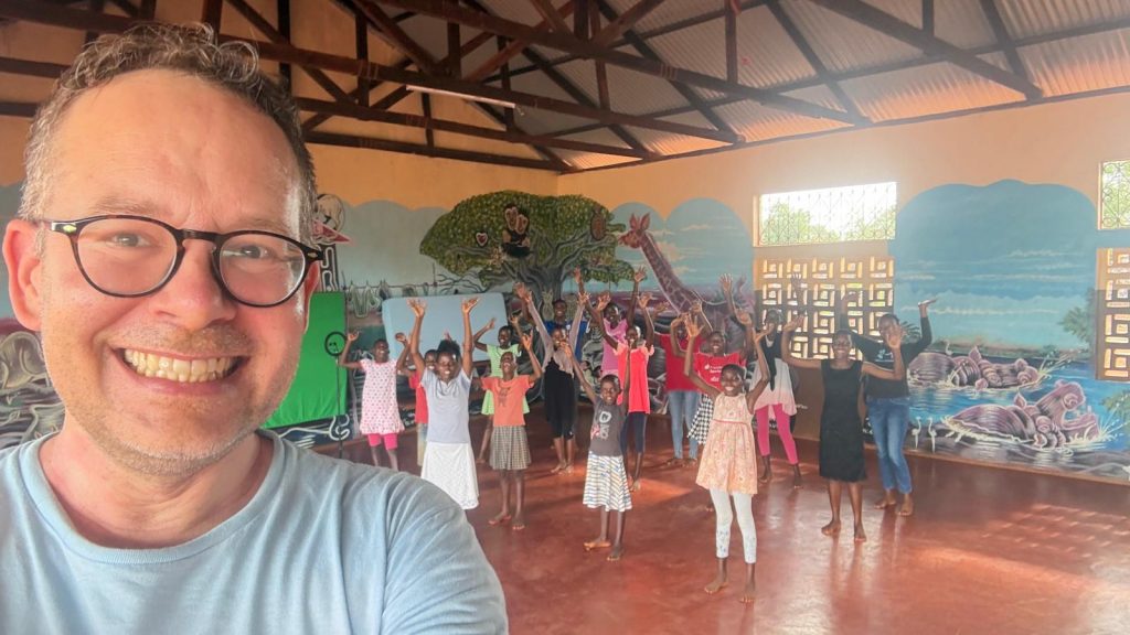 Volker Neuendorf vom Ensemble Voice Ten probt mit den Waisenkinder der Kenia Kinder Hilfe den neuen Weihnachtssong für das Video